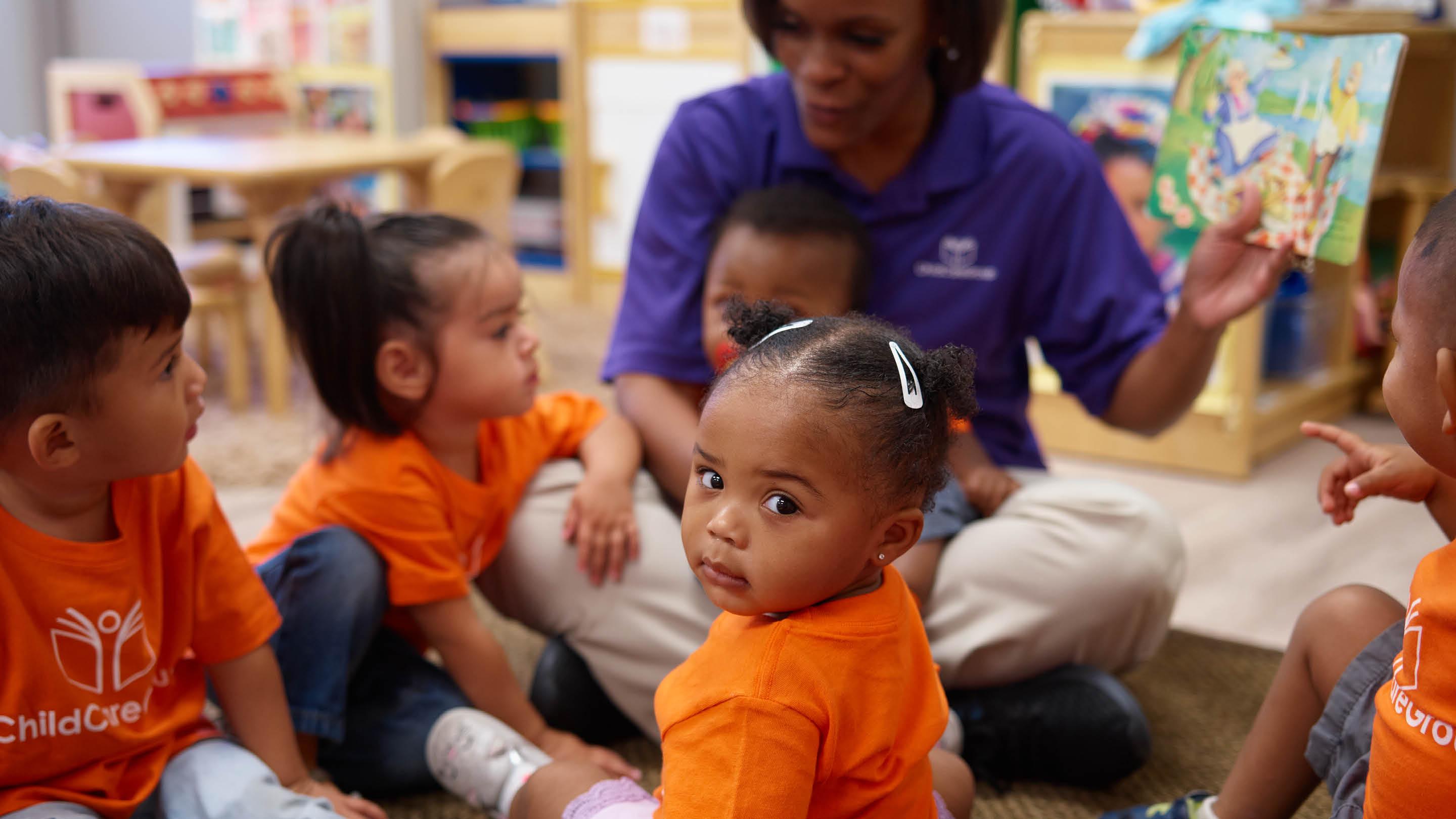 (slide 2 of 7) young children sitting in a group with an adult