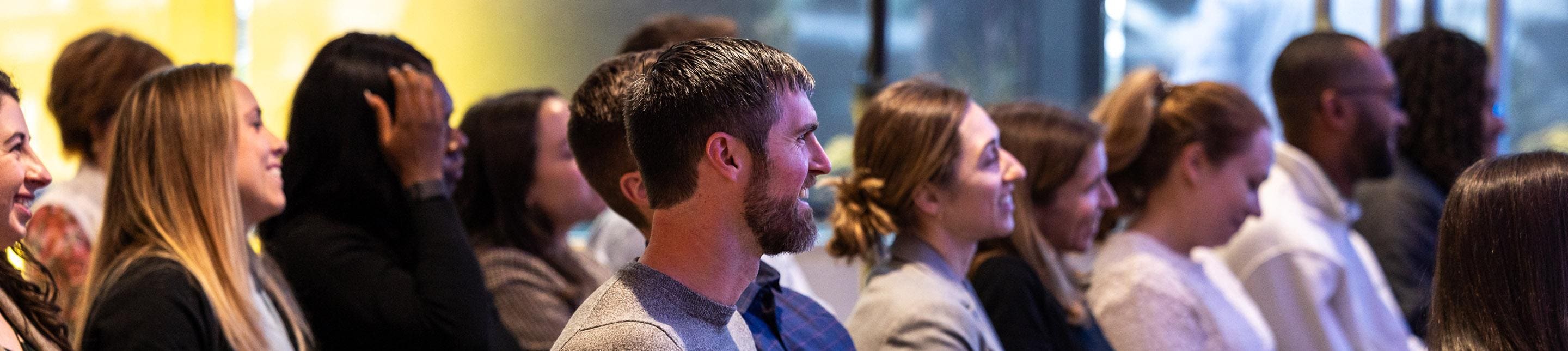 A group of people sitting stadium style in a large meeting - open office concept