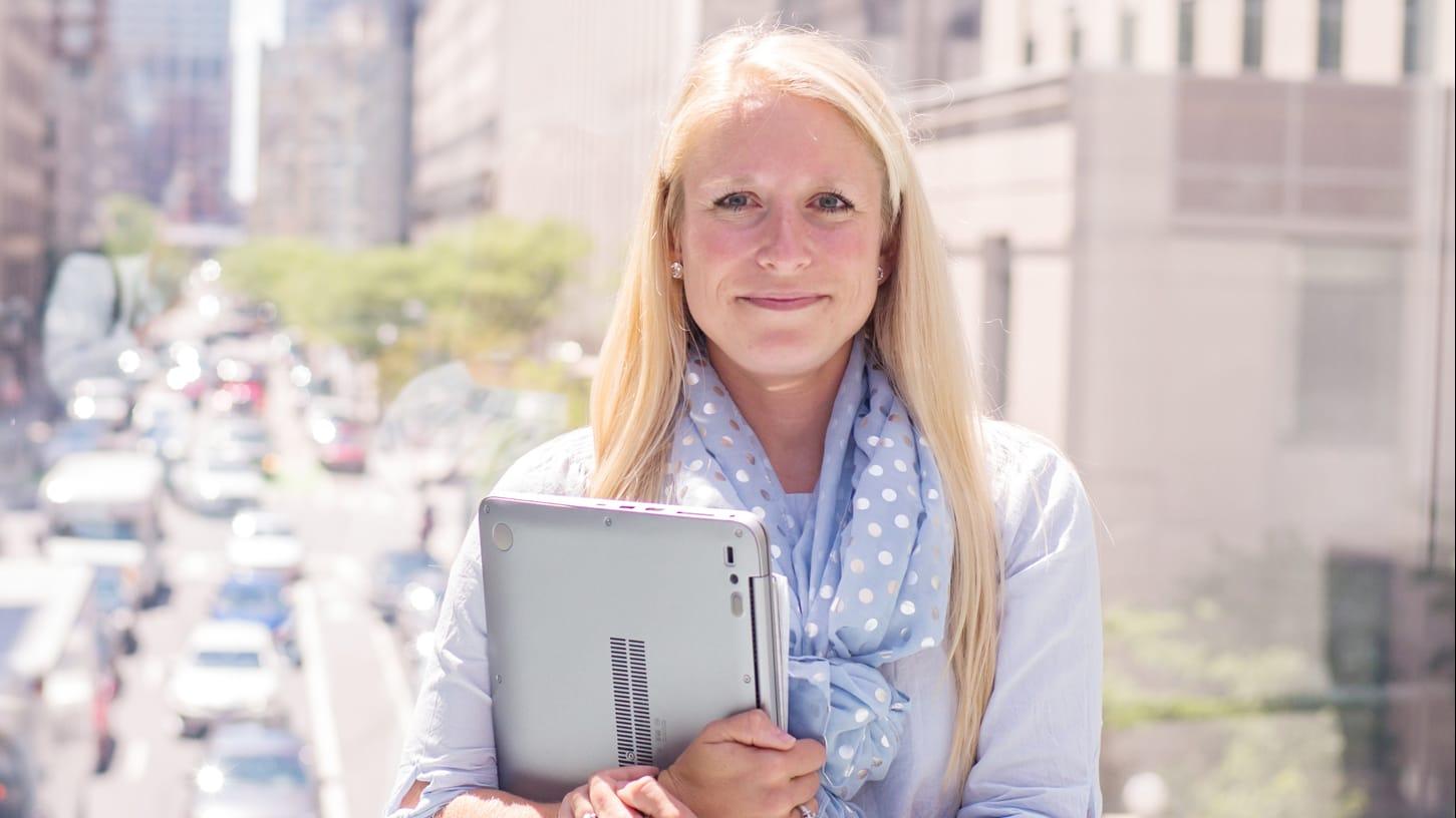 Female graduate standing outside with city street in background