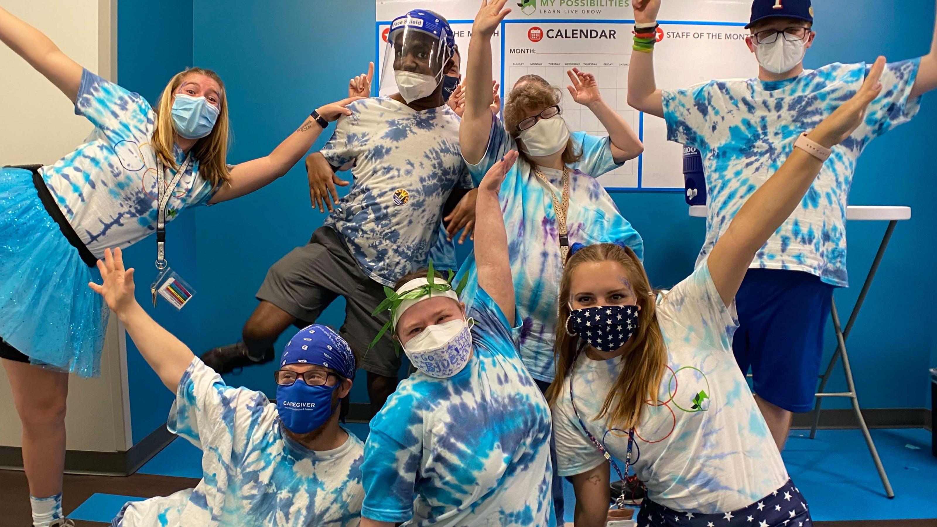 (slide 3 of 4) Young people wearing tie-dye and masks posing and smiling to camera.