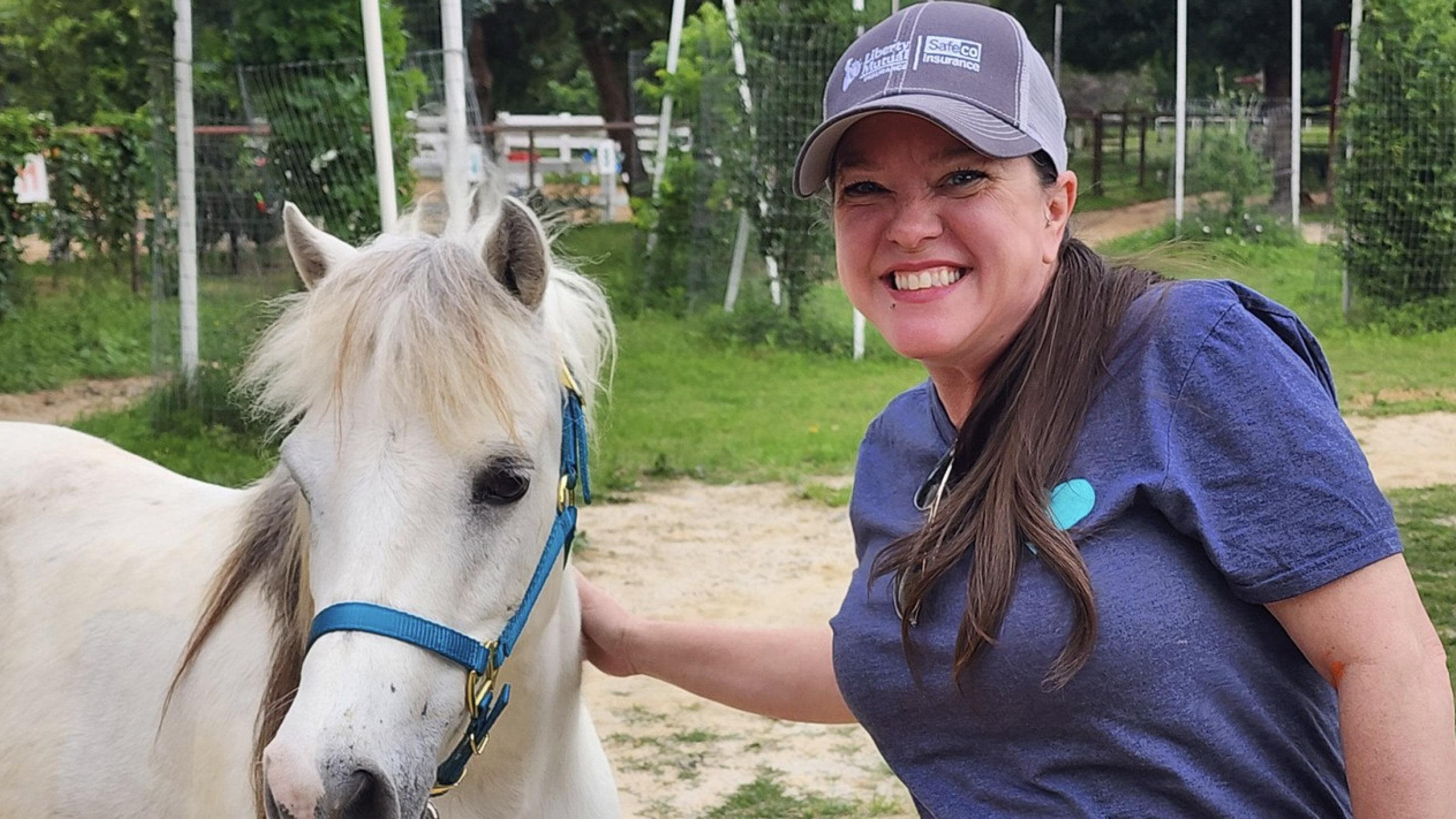 (slide 4 of 8) Amy Nunley of Liberty Mutual posing with a horse, while volunteering.